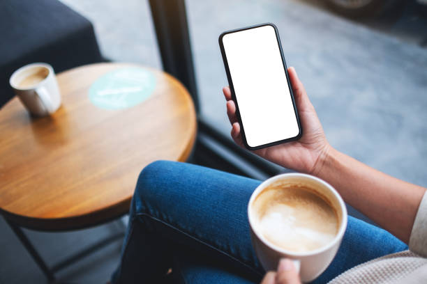 istock a woman holding mobile phone with blank white desktop screen while drinking coffee 1297372730