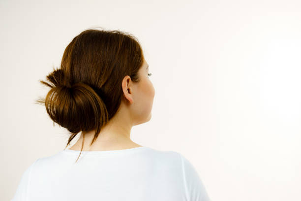 fille avec le long cheveu brun attaché dans le chignon - hair bun hairstyle women hair back photos et images de collection