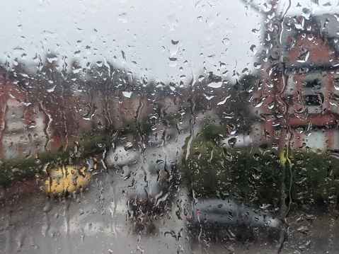 Rain on window blurs cars and houses