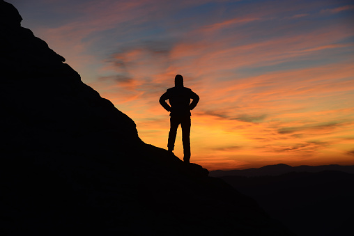 Contemplating sunrise in mountains. Man and mount silhouettes.