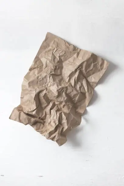 Crumpled craft paper on a white wall. Art object in the design of the studio.