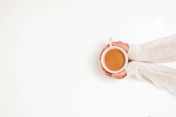 istock Female hands holding cups of coffee on white table background 1297382007