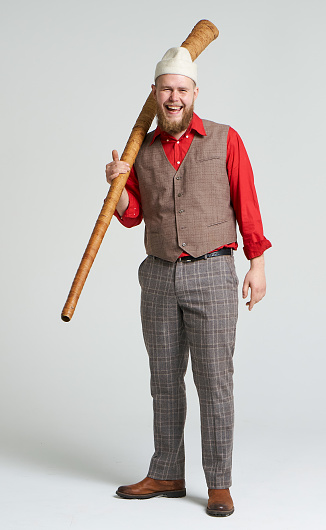 A man trumpet player dressed in traditional mari hats plays traditional Mari folk instruments. He is holding the trumpet (long horn) and looking at the camera. The Mari people belong to the Finno-Ugric ethnic group and live in the Volga region of Russia. A wind instrument resembling a long horn is called a puch. There are varieties of musical trumpets for men (puch) and for women (vuch). Studio shooting on white background