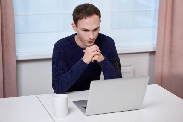 istock A handsome man is working with a laptop. A cup of coffee or tea is on the table. 1297384457