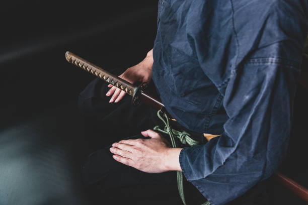 A seated man holding his sword with one hand.