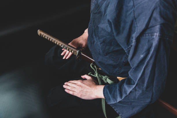 A seated man holding his sword with one hand. stock photo