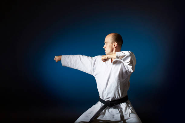 istock Black belt athlete does formal karate exercises on blue background with gradient 1297386561