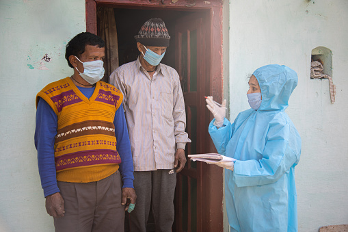 Women nurse workers in ppe kit doing door to door surveys in Indian village regarding Covid-19
