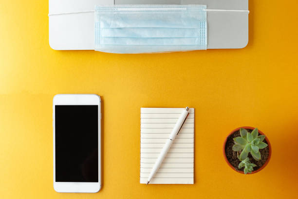 istock Coronavirus Covid-19 Prevention. Remote work or learning in quarantine. Laptop and antiviral medical mask, phone Notepad and pen they lie next to each other. Remote work, office work, freelance 1297389763