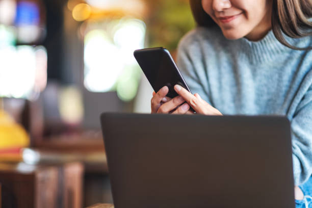 istock a young asian woman holding and using mobile phone and laptop computer 1297389846