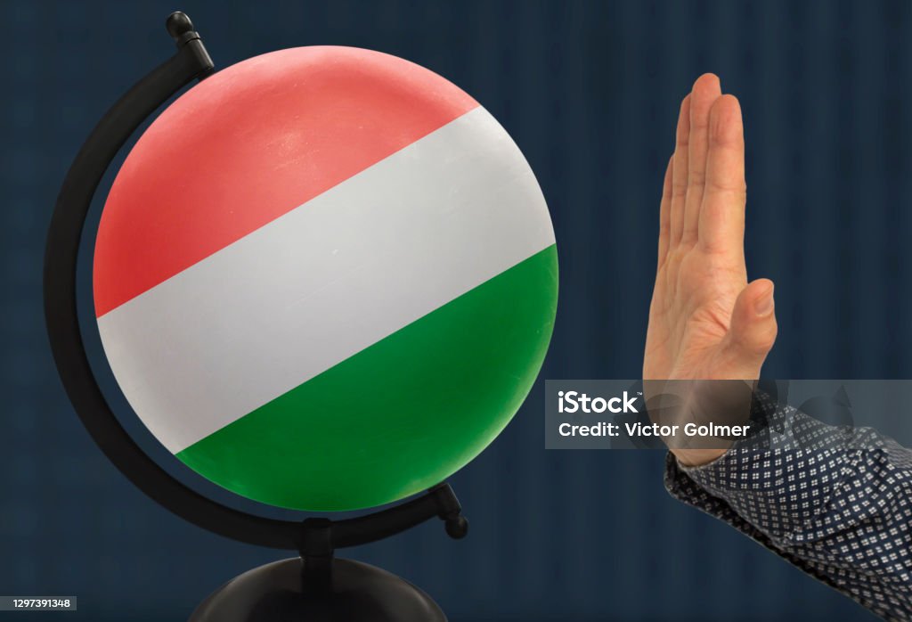 gesture of a male hand warns against the globe, which depicts a colored national state flag Hungarian Business Stock Photo
