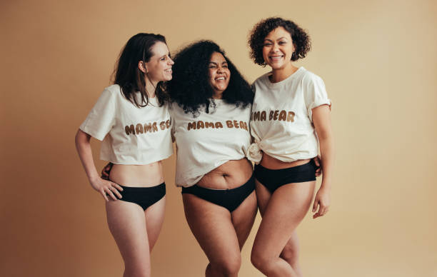 Happy real mothers wearing maman bear t-shirts standing togehter. Beautiful and healthy mothers.