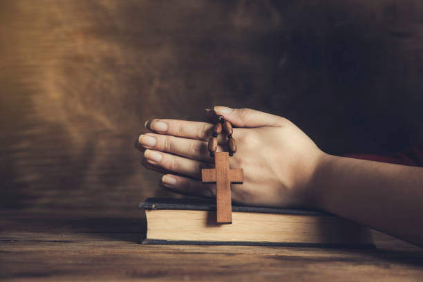 istock woman holding cross on Bible 1297394748