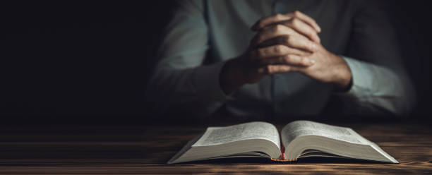 istock prayer hands on a Holy Bible 1297394788