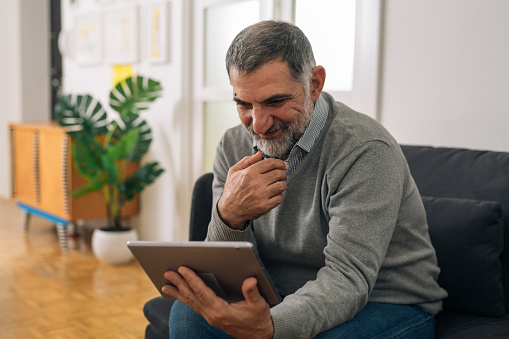 Man Using Digitl Notepad Man Sitting On Sofa And Using Digitl Tablet At His Home Stock Photo ...