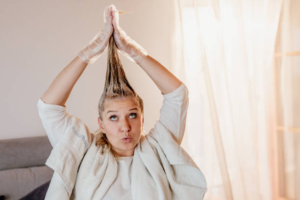 woman coloring her hair at home - hair color dyed hair hair dye human hair imagens e fotografias de stock