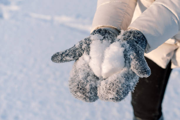 istock Woman holds snow in blue mittens. 1297395823