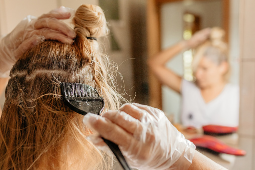 Mujer teñindo el pelo frente al espejo photo