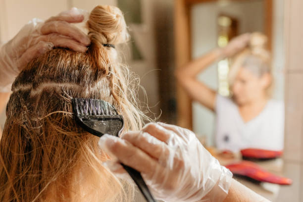 cheveu de teinture de femme devant le miroir - couleur des cheveux photos et images de collection