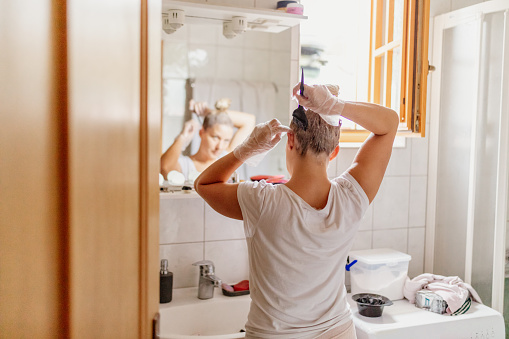 Mujer teñindo el pelo frente al espejo photo