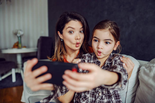 istock Mother and daughter making silly faces and taking a selfie. 1297396852