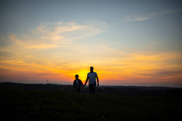 istock Father and son walking on grass during sunset 1297396916