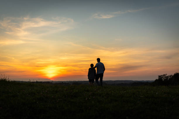istock Father and son arm around during sunset 1297396961