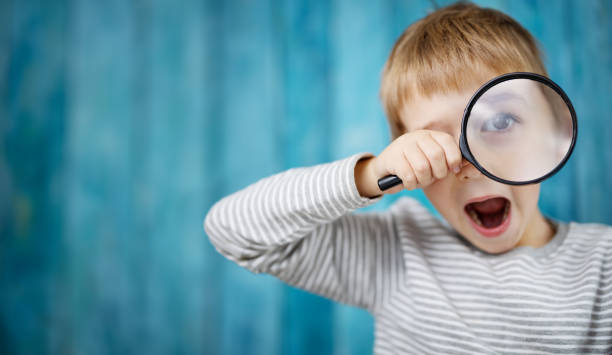 istock Little boy shocked looking through a magnifying glass 1297397058