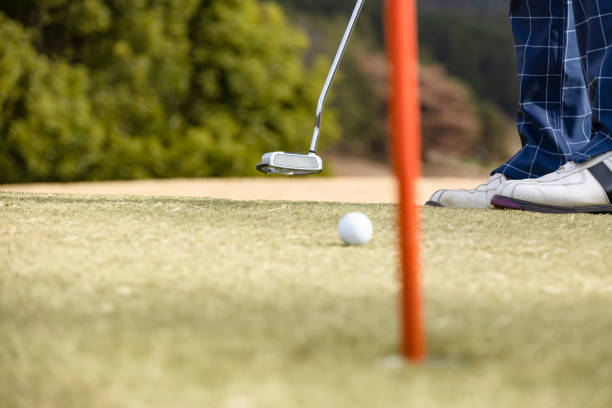 un hombre disparando en un campo de golf - practicing golf putting golf flag fotografías e imágenes de stock