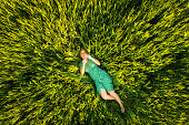 Beautiful woman lying on agricultural field of young wheat