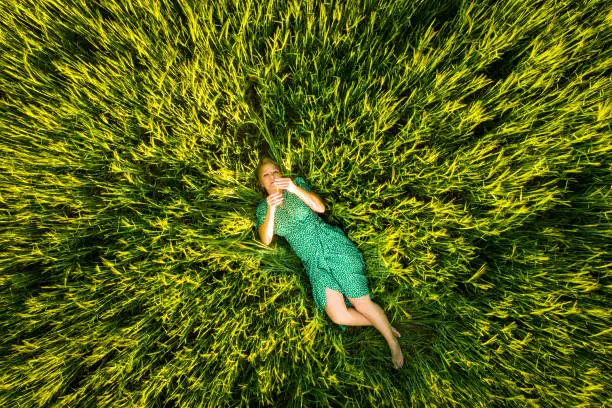 Photo of Beautiful woman lying on agricultural field of young wheat