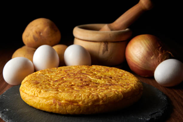 un primo piano di una gustosa frittata spagnola fresca e gli ingredienti sullo sfondo, un piatto tradizionale spagnolo - tortilla spagnola foto e immagini stock