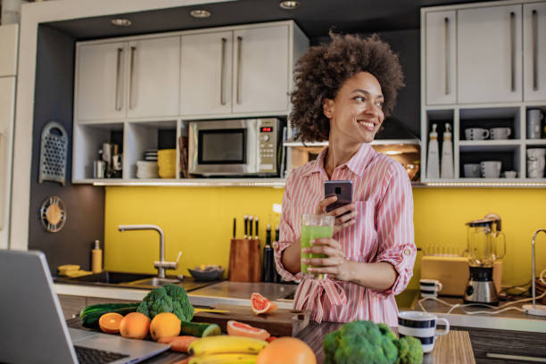 istock Woman is using mobile phone in the kitchen and holding a healthy drink 1297402442
