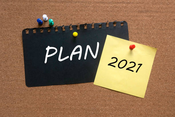 istock A memo note written with Year 2021 and black paper written with word Plan on a cork board. 1297405225
