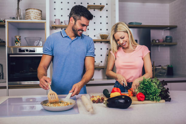 istock Happy couple making lunch together in their kitchen at home 1297405477