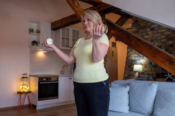istock Mature Woman Is Exercising At Home And Using Cans Instead Of Weights 1297405591