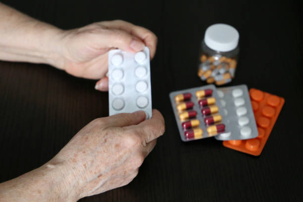 istock Elderly woman with pills in wrinkled hands 1297406491