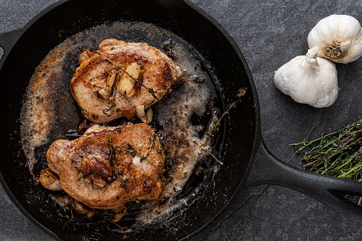 Pan Fried Pork Chops with Thyme, Garlic and Butter in a cast iron skillet