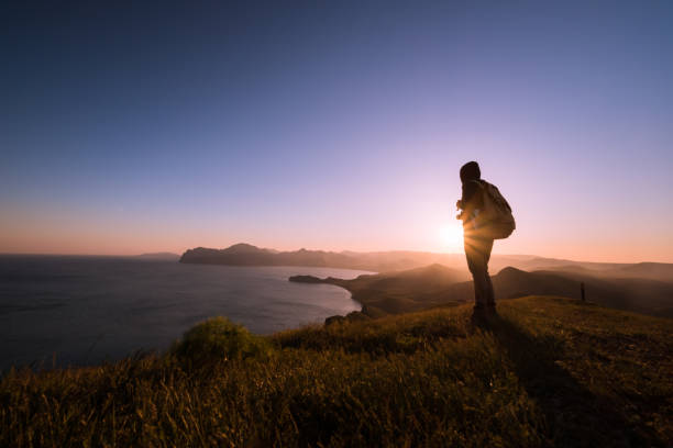 istock Young standing man with backpack. over sunset in nature 1297406870