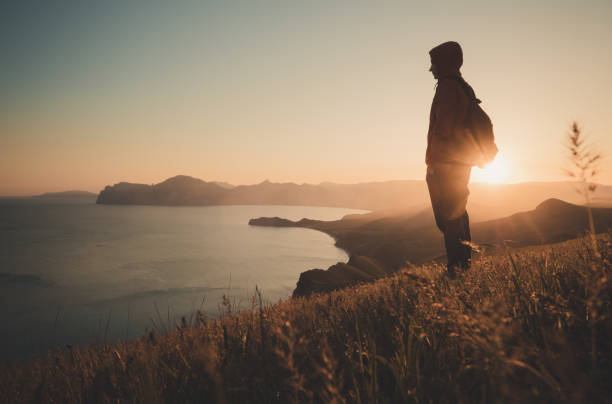 istock Young standing man with backpack. over sunset in nature 1297407150