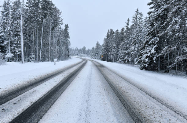 istock Snow covered road in snowstorm creating dangerous driving conditions 1297407857