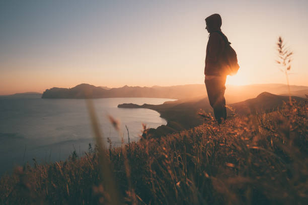 istock Young standing man with backpack. over sunset in nature 1297408257