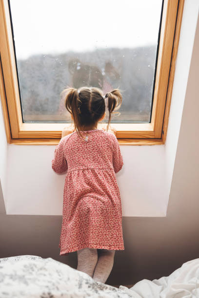 istock Curious little girl looking out the window 1297408704