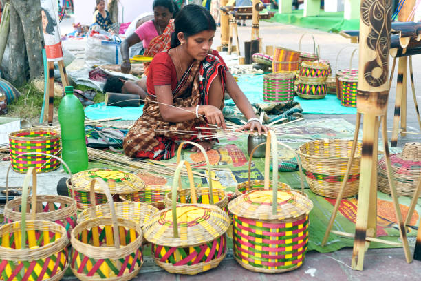 A woman artisan making bamboo made baskets and other handicrafts at Saras Mela, in Kolkata Kolkata, 03/01/2020: A lady artisan from rural community making bamboo / cane made handicrafts at Saras Mela, a handicraft fair organised annually to showcase West Bengal's handicraft. Several finished products are on retail display for sale. india indian culture market clothing stock pictures, royalty-free photos & images