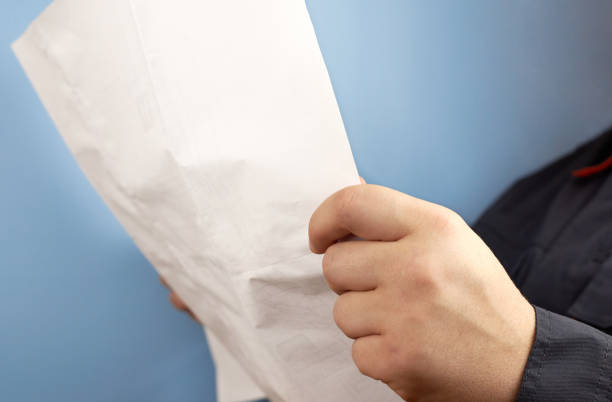 istock A man in his hands holds a document or drawing on a blue background. 1297410294