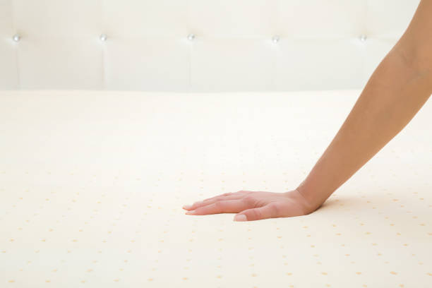 Young adult woman hand pressing yellow rubber foam mattress surface. Checking hardness and softness. Choice of the best type and quality. Closeup. Young adult woman hand pressing yellow rubber foam mattress surface. Checking hardness and softness. Choice of the best type and quality. Closeup. latex stock pictures, royalty-free photos & images