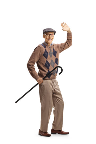 istock Elderly gentleman holding a cane and greeting with hand 1297411246