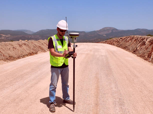 Geodetic engineer surveyor in white hard hat doing measurements with GNSS satellite receiver
