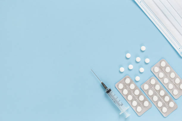 istock Medical face mask, packaging with pills, expendable syringe for vaccination. Vaccination concept against various infection diseases. 1297414389