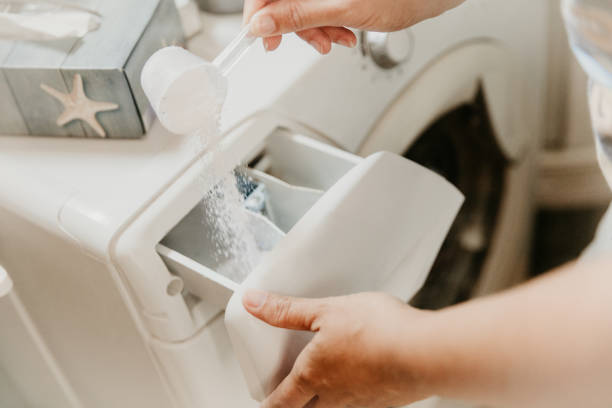 Pouring washing powder in washing machine Woman pouring washing powder detergent in washing machine at home laundry detergent stock pictures, royalty-free photos & images